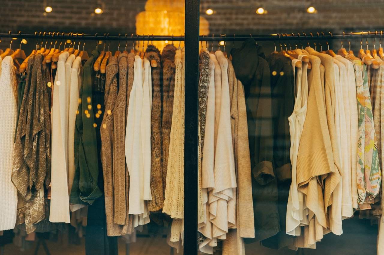 Vintage clothing store with a variety of stylish sweaters and jackets hanging on a rack, showcasing autumn fashion trends and warm wardrobe essentials.