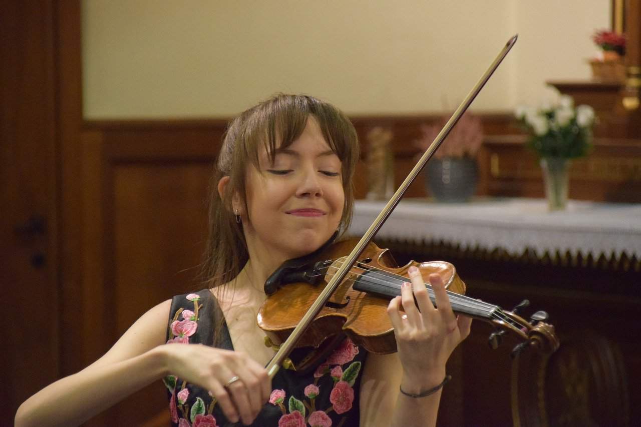 Playing classical violin in a performance setting, showcasing musical talent and stage presence.