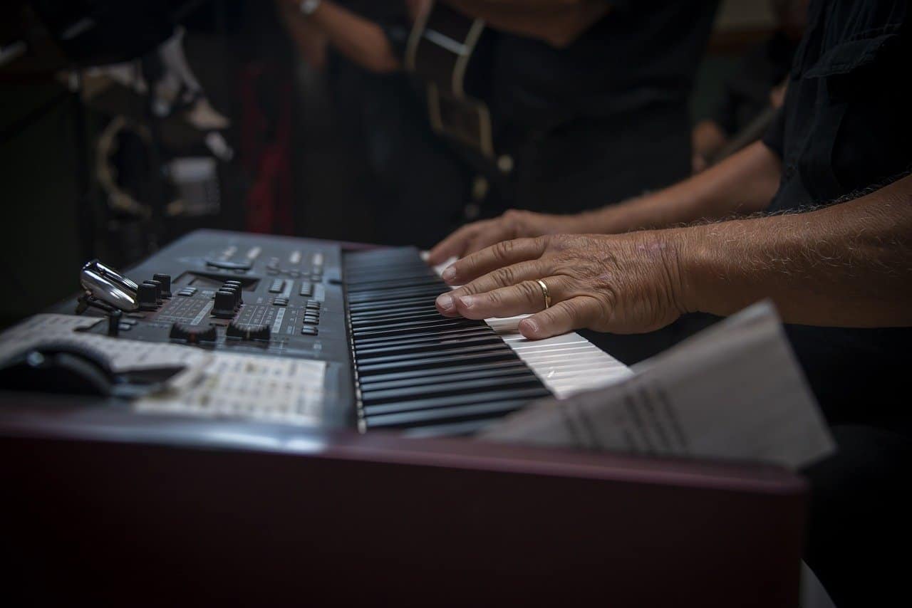 Keyboard musician playing synths during live performance at a music event.