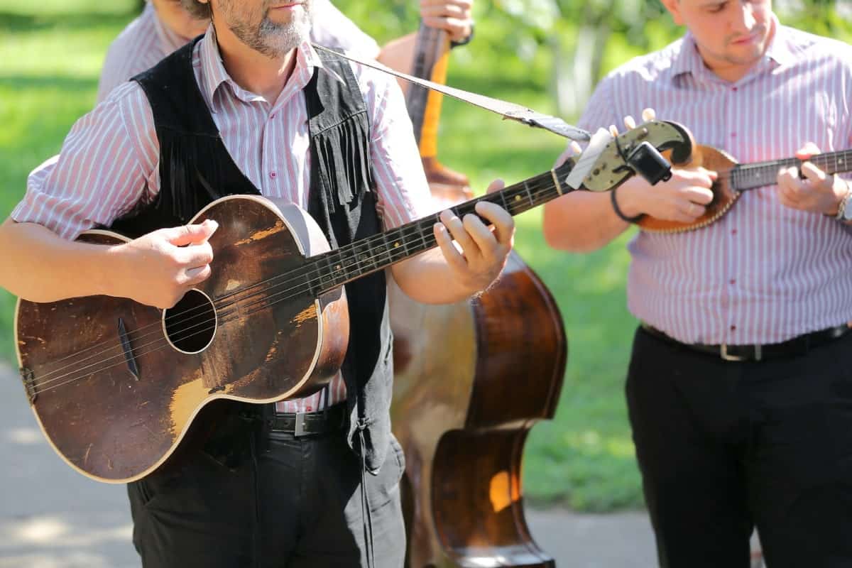 Guitar and mandolin players performing outdoors at a music event.