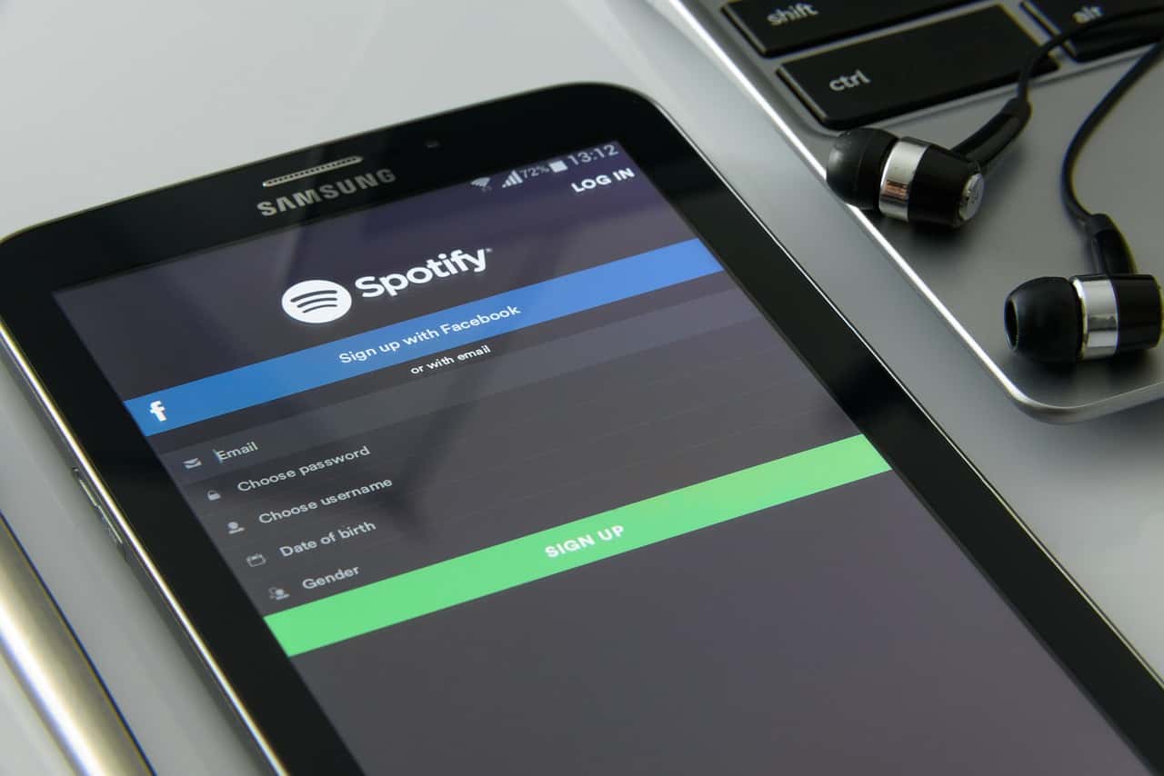 Spotify login screen on a smartphone with earphones and laptop, music streaming app, digital music platform, online music service, tech gadgets for music listening, SEO optimized image.