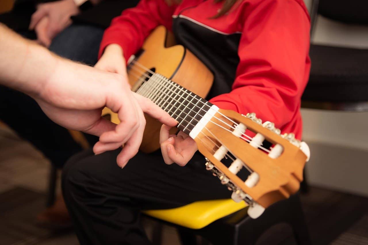 Guitar lesson, beginner guitar instruction, guitar tuning, music education, learning acoustic guitar, one-on-one guitar coaching, musical instrument training, guitar practice session, playing acoustic guitar, youth guitar lessons.