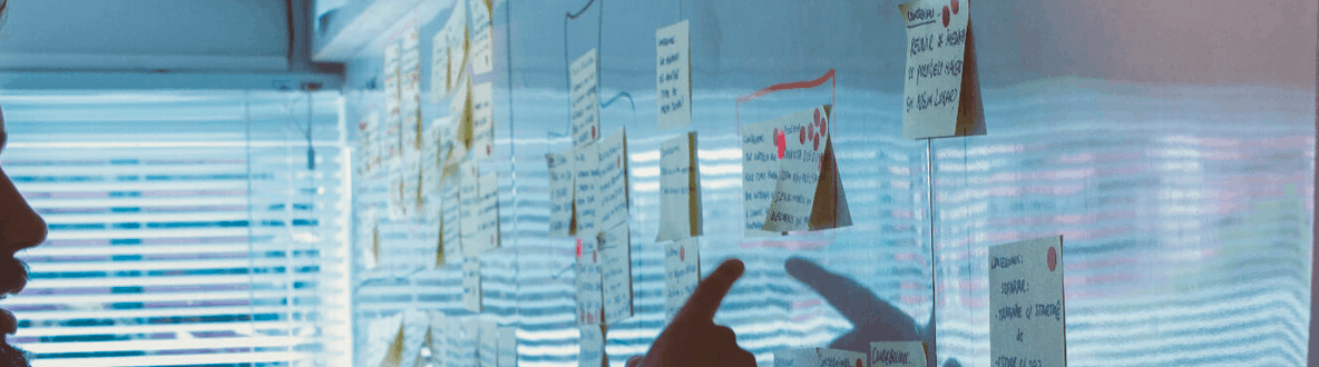 A person interacting with a transparent board filled with colorful sticky notes and notes, indicating brainstorming and creative planning in the music industry or digital marketing context.