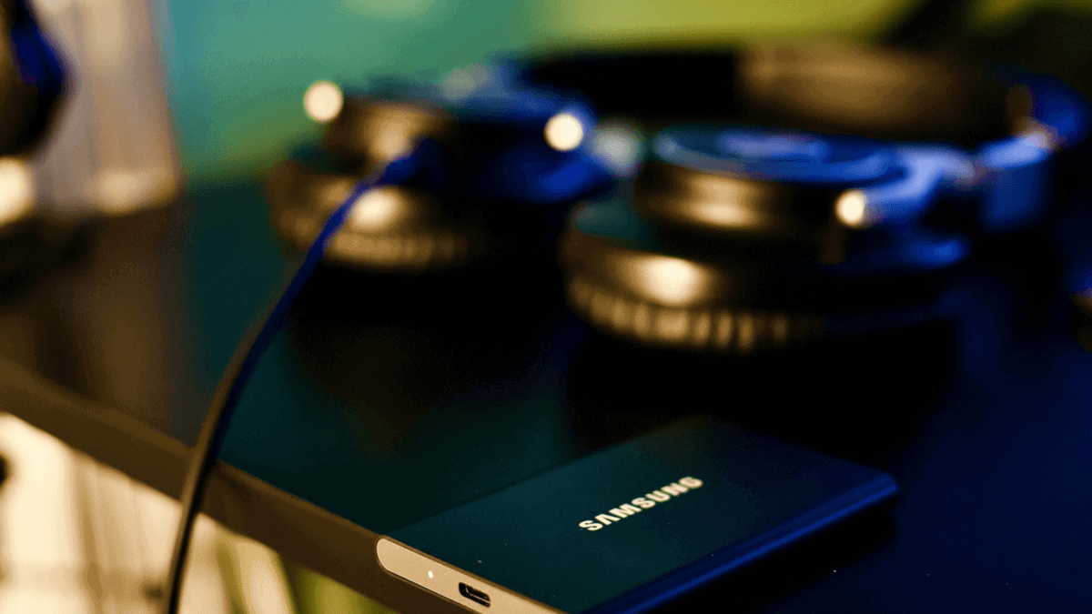 Samsung smartphone with headphones and a computer mouse on a desk, tech gadgets for music and digital media, modern electronic devices for entertainment and work.