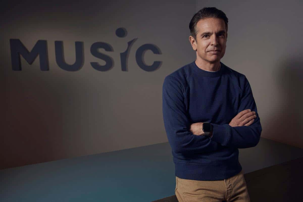 Professional man standing with arms crossed in front of a music-themed background at Hypebot event.