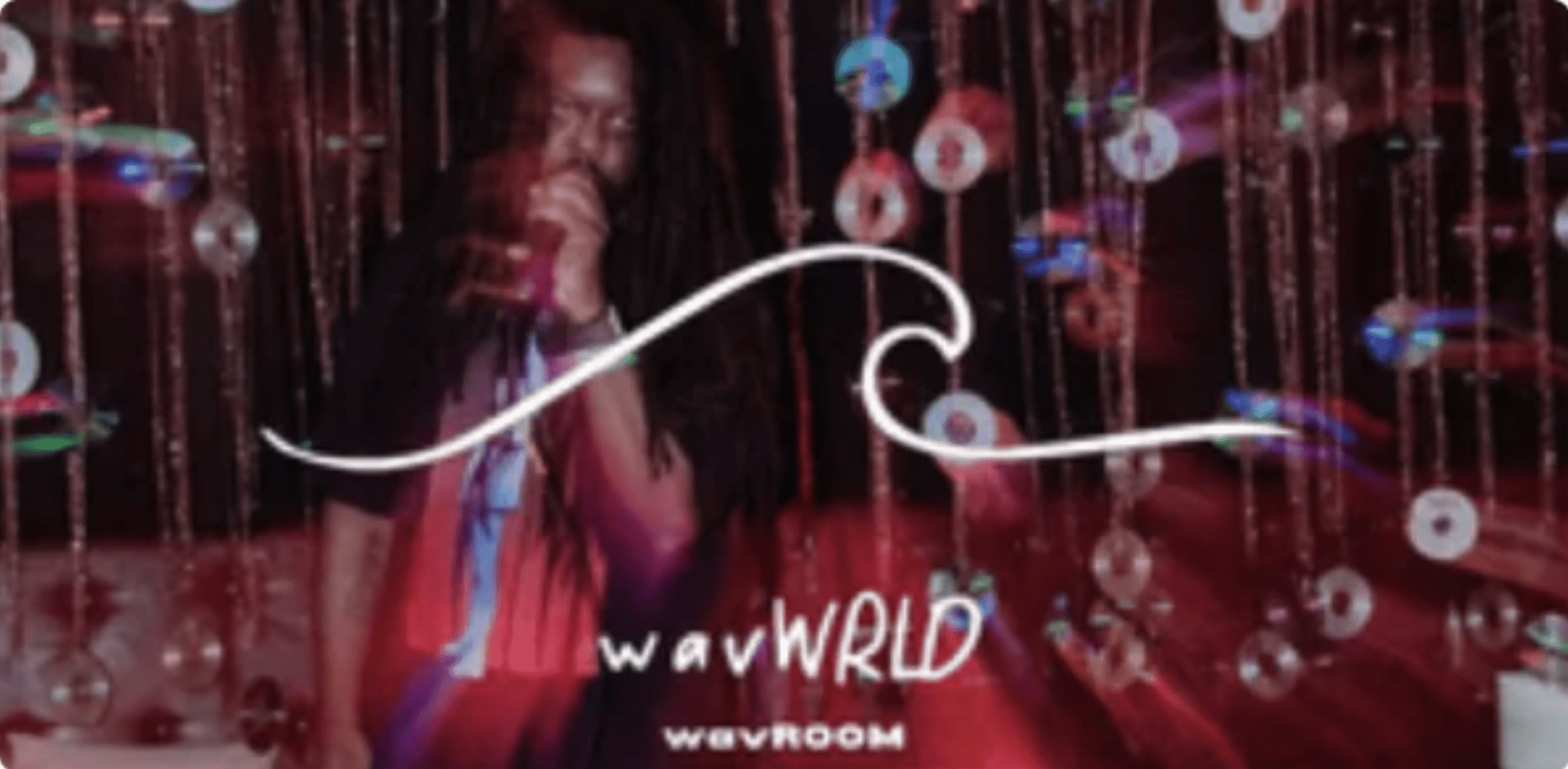 Rainbow-colored disco ball backdrop with illuminated text displaying "wave" and "WAVWORLD" at a music event or festival, vibrant party atmosphere, digital art, entertainment, nightlife scene, music culture, vibrant lighting, energetic environment, nightlife, and electronic music inspiration.