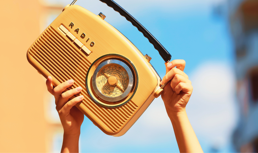 Radio vintage portable radio held up in the air outdoors, symbolizing music, broadcasting, and entertainment in digital marketing.