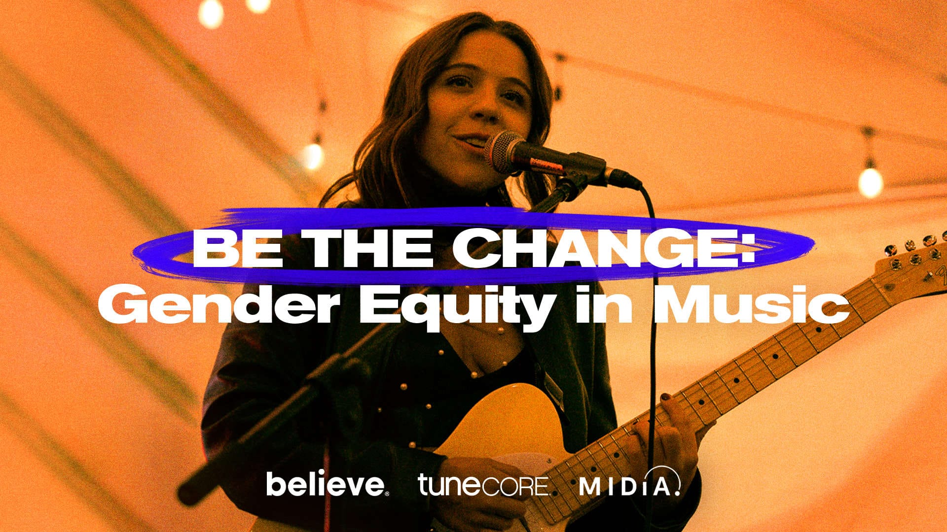 Empowering women in music, a female musician passionately performs with a guitar and microphone at an event promoting gender equity in the music industry.