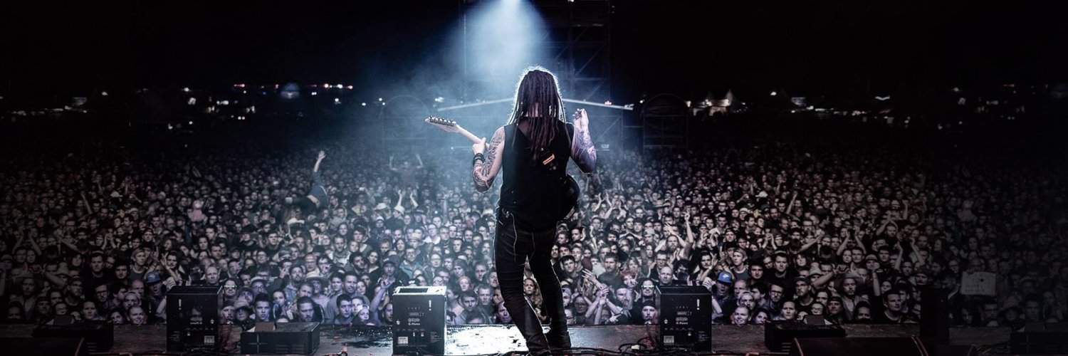 Vocalist performing on stage in front of a large, packed audience at a music concert, with stage lighting illuminating the crowd and creating an energetic atmosphere for live music events and entertainment.