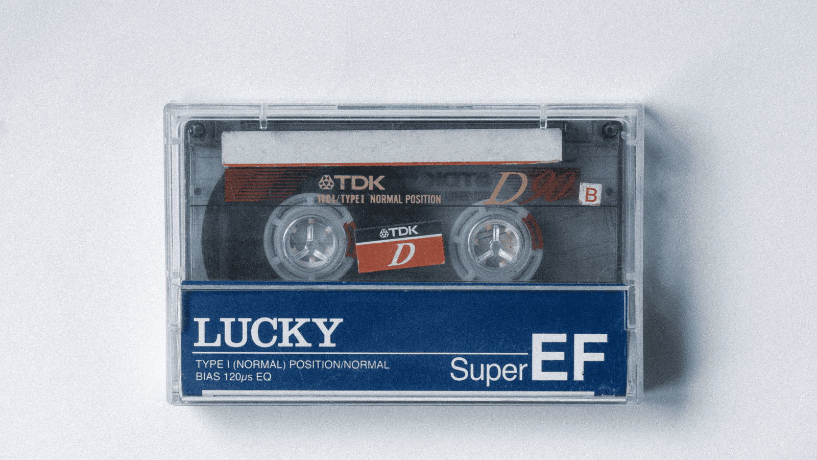 A compact audio cassette tape with clear plastic casing showing the reel and label, labeled "Lucky Super EF," used for music or voice recording, vintage media format.