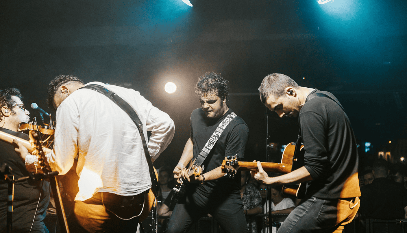 Guitarist band performance at live music event, musicians playing guitars on stage, energetic concert scene, diverse group of musicians, vibrant atmosphere, music industry event, Hypebot coverage.