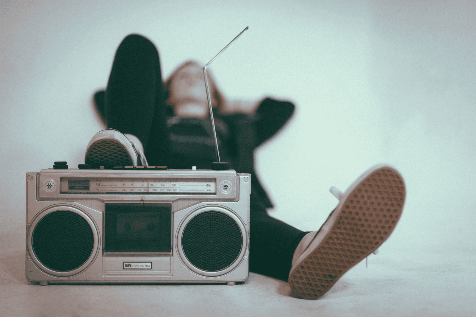 Retro portable radio and a woman relaxing with her feet up, surrounded by music and entertainment elements, symbolizing music technology, relaxation, and lifestyle trends.
