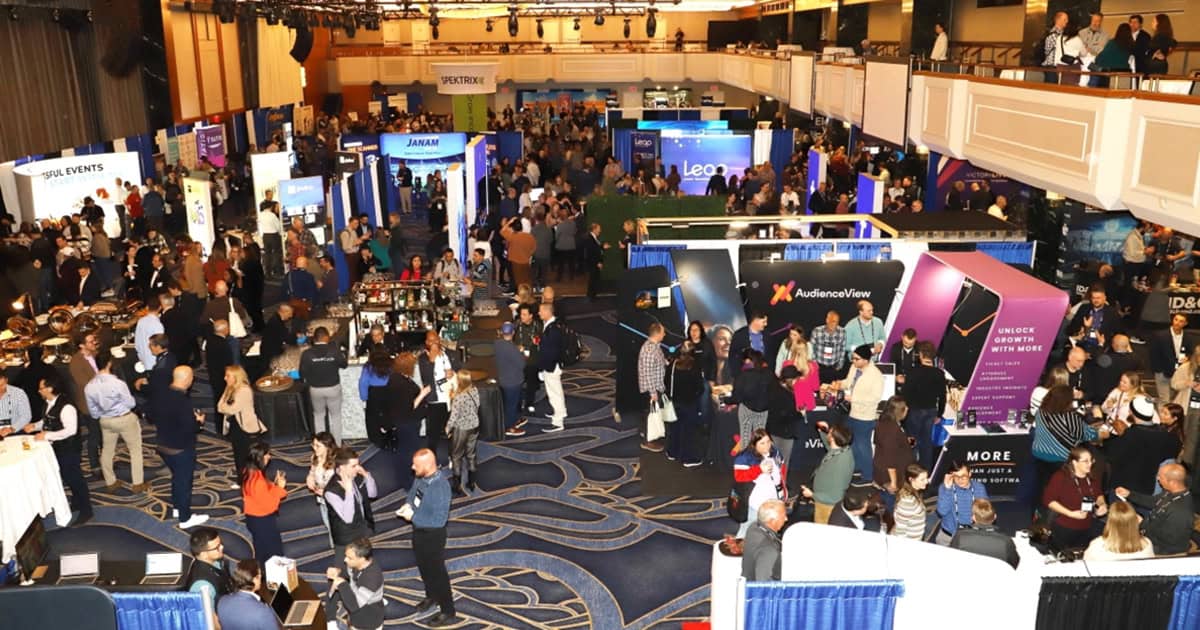 Crowd attending music industry conference at a busy expo hall with multiple exhibition booths and networking areas, showcasing the latest trends in digital media and entertainment technology.