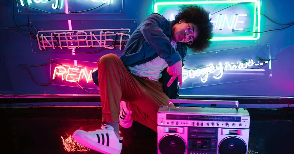Vibrant neon-lit scene with a young person dancing and pointing at a vintage boombox, showcasing music, dance, street art, and nightlife culture in a colorful urban setting.