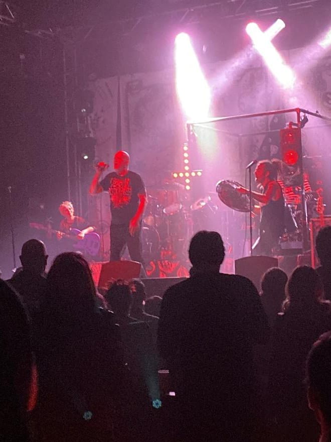 A live music concert featuring a band performing on stage with dynamic lighting and an engaged audience enjoying the show. The scene captures the energy and atmosphere of a vibrant music event.