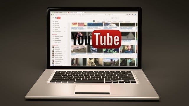 High-resolution laptop showing YouTube homepage with various video thumbnails and a prominent YouTube logo.