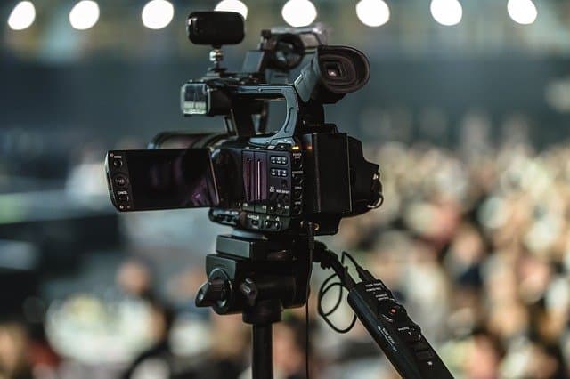 Professional video camera setup on a tripod capturing live event, focus on broadcast quality recording for media production and content creation.