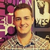 Young man smiling at Hypebot event, music industry professional in casual attire, vibrant background with music and branding elements.