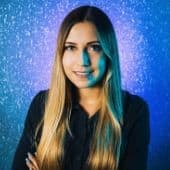 Teen girl with colorful hair smiling against glittery blue background, representing modern youth culture and trendsetting style.