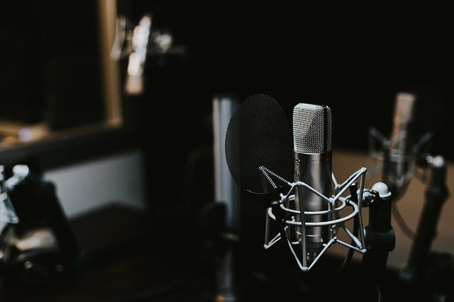 Broadcast microphone and pop filter in a professional recording studio for podcast or music production.