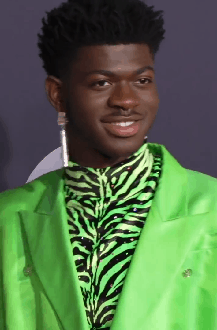Vibrant image of a young man wearing a neon green suit with a zebra print shirt, showcasing bold fashion choices at a music or entertainment event for Hypebot.