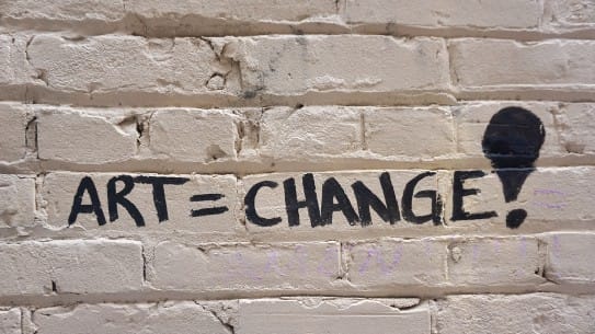 Art change graffiti on brick wall supporting social activism and cultural transformation for arts and community engagement.