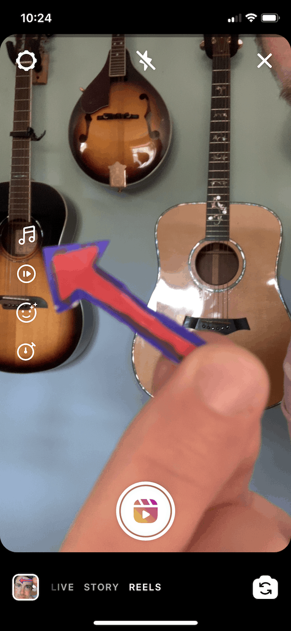 Guitar wall display with various acoustic guitars, bright indoor lighting, and a person holding a colorful arrow sticker for creative social media content.