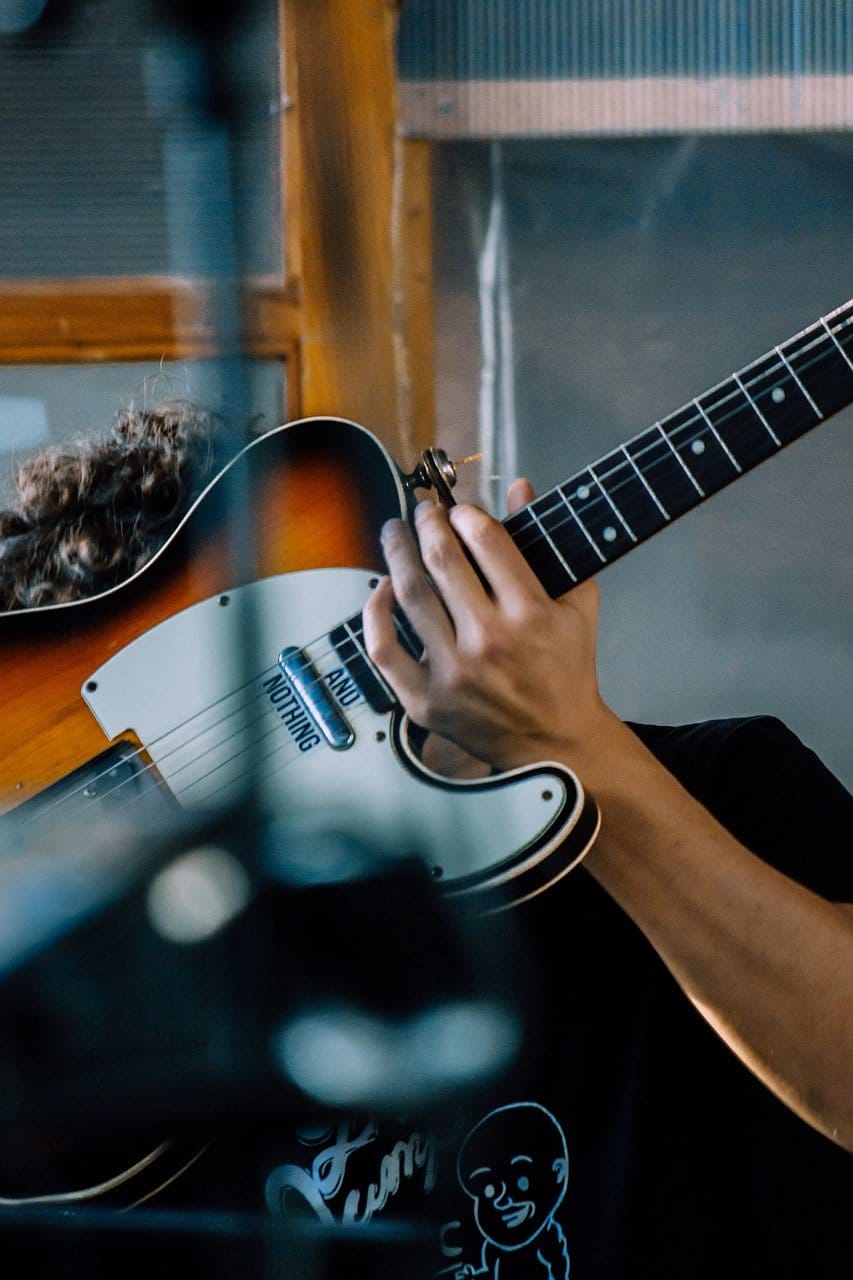 Vintage electric guitar being played, musician in a recording studio, music production, guitar performance, music studio setting.