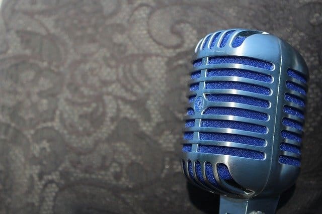 Shiny vintage blue microphone on textured dark surface, ideal for music, podcast, or radio broadcasting content.