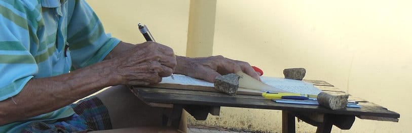 Handwritten notes on a wooden desk with pens and rocks, outdoor setting, capturing the essence of traditional writing and note-taking, possibly in an academic or personal context.