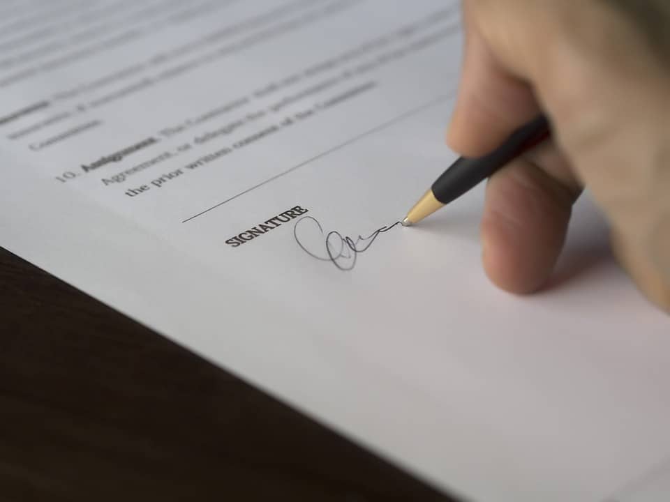 Legal document signing with a pen on paper, close-up of signature process.