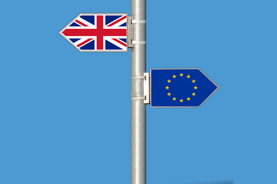 UK and EU flag directional signs against blue sky, symbolizing international trade and policies, relevant for discussions on Brexit, European Union membership, and global music distribution platforms like Hypebot.