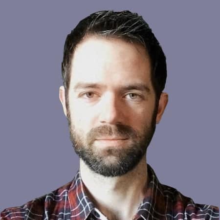 Professional male with dark hair and beard wearing a plaid shirt, portrait against a neutral background, suitable for technology and music industry content.