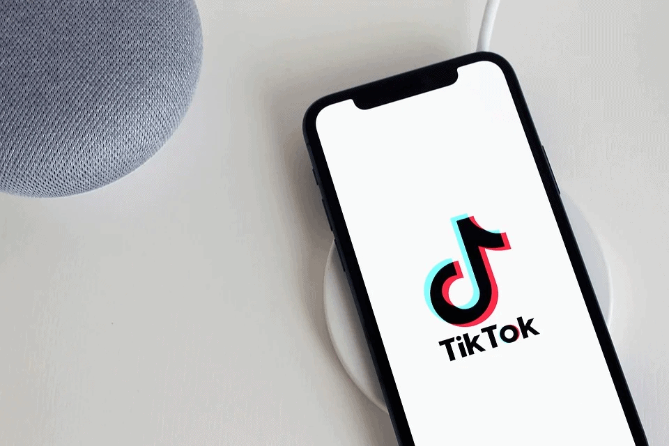 TikTok app on a smartphone placed on a wireless charging pad, showcasing the popular social media platform for short videos, digital entertainment, and trending content creation.