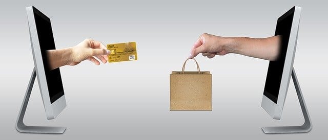 Online shopping transaction between two computer screens showing credit card and shopping bag, e-commerce, digital marketplace, internet commerce, online retail, Hypebot.