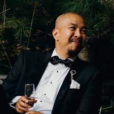 Elegant man in tuxedo holding a glass of champagne at a formal event, smiling and enjoying the celebration.