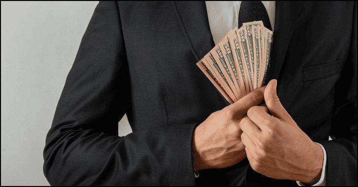 Theft of money from a businessman in a suit, holding cash secretly in a pocket, representing financial crime or corruption.