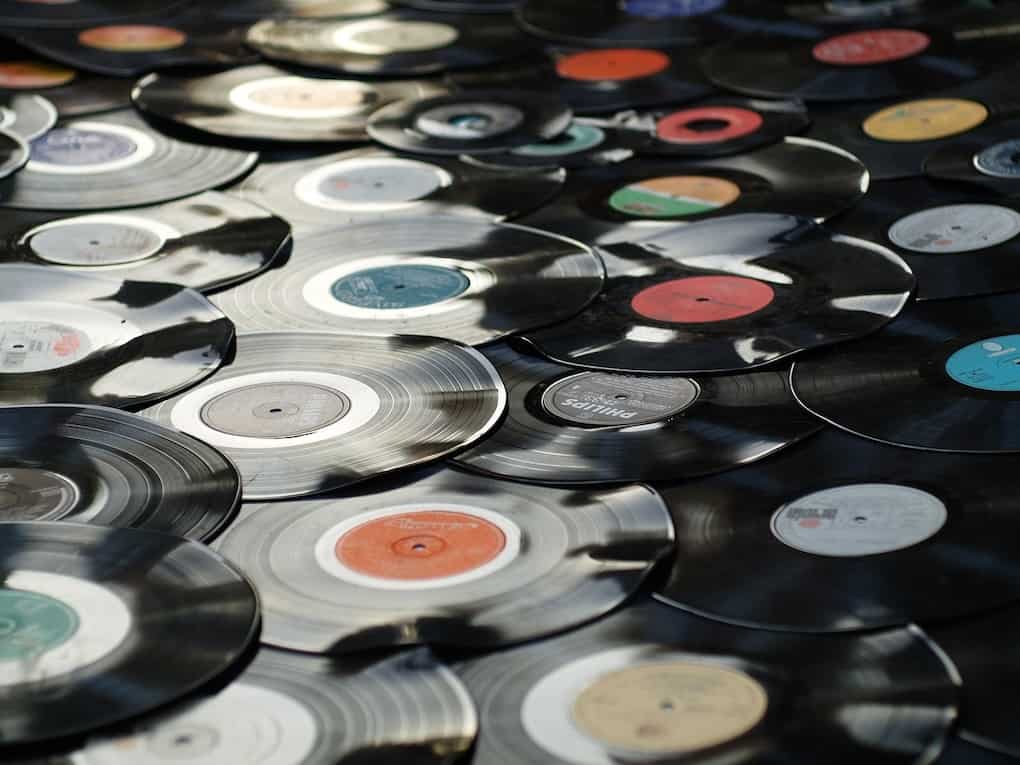 Shiny scattered vinyl records with colorful labels, reflecting light, creating a vibrant retro music vibe. Ideal for music, vinyl, record collection, and nostalgia themes.