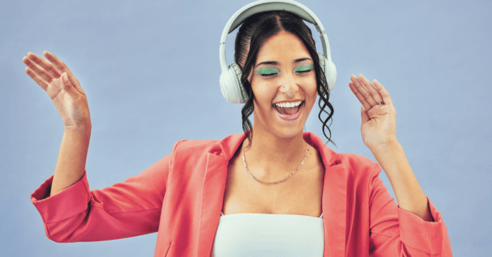 Vibrant young woman enjoying music with headphones, celebrating good sound quality and musical experience.