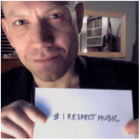 A man holding a sign that says #IRespectMusic symbolizes support for music creativity and industry.