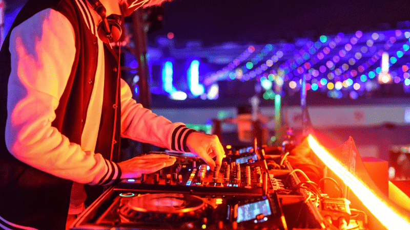 High-energy DJ performing at a vibrant outdoor music festival with colorful LED lights and a lively atmosphere.