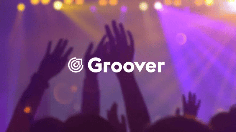 Groover music streaming app logo with concert crowd and colorful stage lighting in the background—ideal for music industry, artist promotion, and digital distribution SEO.