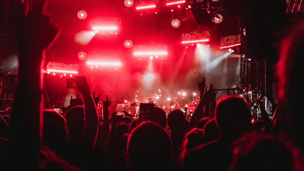 Vibrant live music concert with audience enjoying performances, illuminated by dynamic red stage lighting, capturing the energy and atmosphere of a modern concert scene.