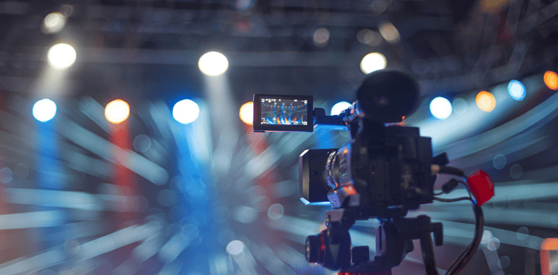 Camera recording live music performance at concert, professional video production, stage lighting, event filming, entertainment industry, Hypebot.