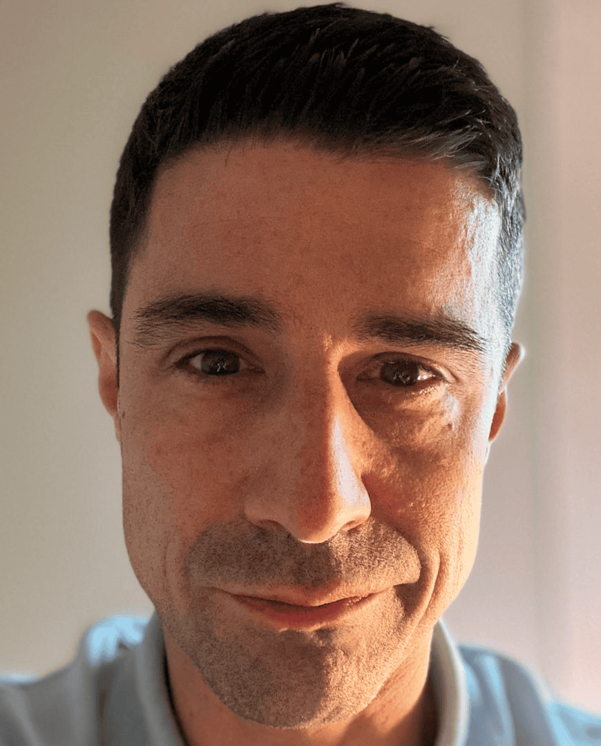 Headshot of a smiling man with short dark hair and light skin, close-up portrait, natural lighting, casual clothing, professional appearance, suitable for social media and profile images.