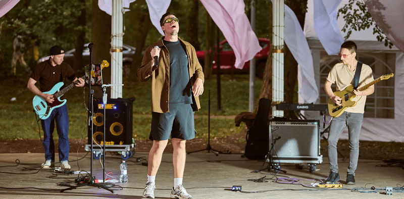 Music performance by indie band at outdoor festival with colorful flags, live concert, musicians with instruments, summer event, entertainment, artist community, Hypebot music news relevance.