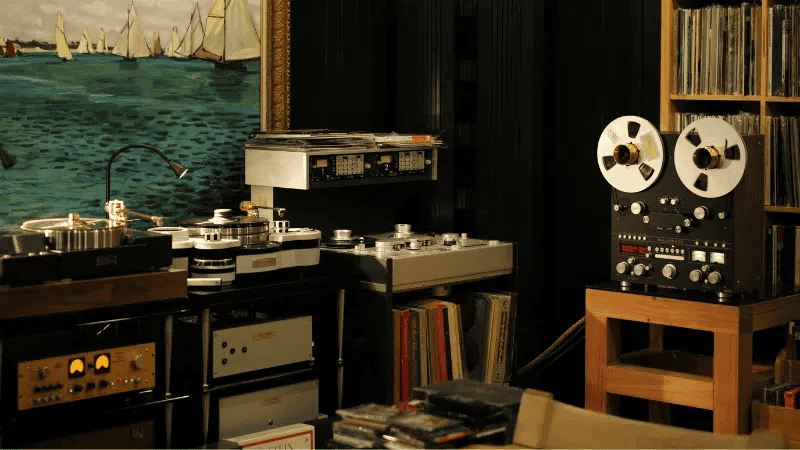 Vintage audio equipment setup in a music enthusiast's room with turntables, reel-to-reel tape recorder, and vinyl records. Perfect for high-quality sound and music production or listening enjoyment.