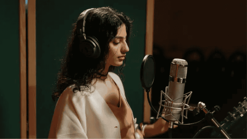 Female singer recording in a professional studio with headphones and microphone, music production, vocal recording, sound engineering, music industry, artist recording song, professional vocal performance, Hypebot music news and analytics.