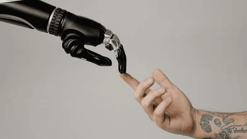 A robotic hand touching a human finger, symbolizing human-robot interaction and artificial intelligence.